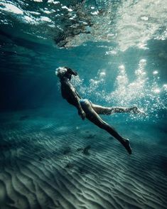 a woman is swimming in the ocean with her legs spread out and head above water's surface