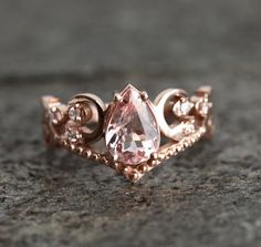 a pink diamond ring sitting on top of a gray stone surface with diamonds around it