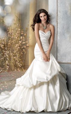 a woman in a wedding dress leaning against a wall