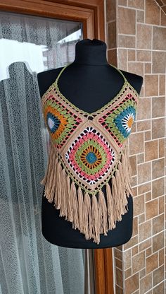 a woman's top with crochet and fringes hanging on a mannequin