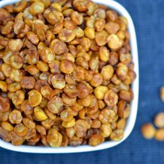 a white bowl filled with roasted chickpeas on top of a blue table