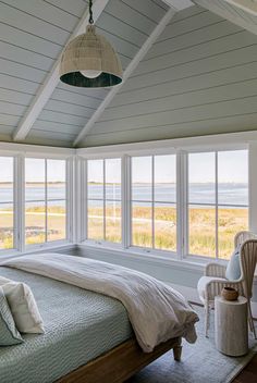 a bedroom with white walls and wooden flooring next to a large window that looks out onto the ocean