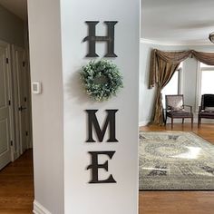 there is a sign that says home with a wreath on the wall next to it