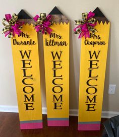 three yellow welcome signs with pink bows on them sitting in front of a white wall