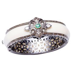 A stunning cuff bracelet in white Bakelite bordered on both sides with pave` set diamonds. The top features additional pave` set diamonds with an oval, faceted emerald and two rose-cut diamonds on each side. Inside circumference is 6 1/8th inch. Perfect for those small wrists. The cuff itself is an oval shape which helps to keep the lovely workmanship and stones on the top of the wrist. Carat weight of diamonds is 4.10; emerald is .35 carats. John Hardy, Rose Cut Diamond, Both Sides, Rose Cut, Oval Shape, Cuff Bracelet, Cuff Bracelets, Diamond Cuts, Jewelry Bracelets