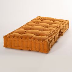 a close up of an orange cushion on a white surface with no one around it