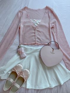 a white skirt, pink shirt and heart shaped purse are on a bed with shoes