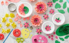 paper flowers, scissors and other crafting supplies laid out on a marble table top