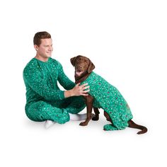 a man in green pajamas petting a brown dog