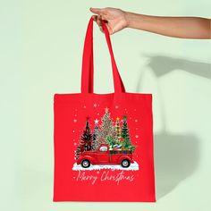 a person holding a red shopping bag with christmas trees on it and a truck in the background