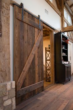 an open barn door in the middle of a room with wood floors and exposed beams