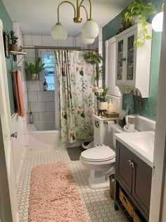 a bathroom with a pink rug on the floor and shower curtain over the toilet area