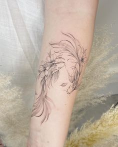 a black and white photo of a woman's arm with a fish tattoo on it