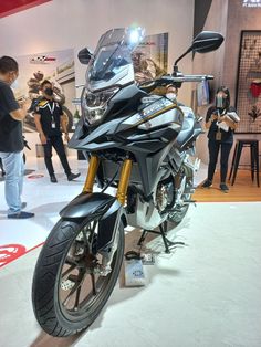 a motorcycle is on display at an indoor showroom while people look around the room