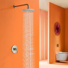 an orange bathroom with a shower head and thermostaer on the wall next to it