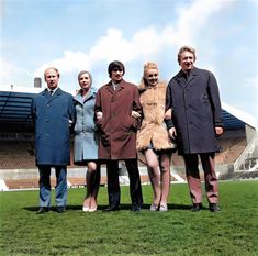 a group of people standing next to each other on top of a lush green field