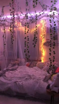 an unmade bed with white sheets and string lights hanging from it's ceiling