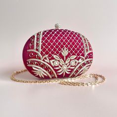 A timeless and classic piece, handcrafted with detailed embroidery and pearl beads. The maroon tones and gold threaded embroidery adds a luxurious feel to the bag and brings the statement factor to your look. With one main compartment and a magnetic fastening, this grande clutch is completed with a chain strap which can be worn as a shoulder bag or tucked in for a clutch style. Elegant Embroidered Fabric With Pearl Embroidery For Reception, Elegant Pearl Embroidered Fabric For Reception, Elegant Hand-embellished Embroidered Fabric For Festive, Elegant Formal Embroidered Fabric With Intricate Embroidery, Festive Embroidered Evening Bags, Elegant Hand Embellished Embroidered Fabric For Festive, Elegant Intricate Embroidery Fabric For Evening, Elegant Hand Embellished Embroidered Fabric For Festive Season, Festive Evening Embroidered Bags