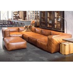 a brown leather couch sitting on top of a cement floor next to a wooden table