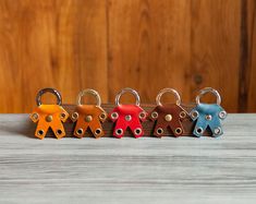 four different colored keychains sitting on top of a wooden table next to each other