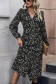 a woman wearing a black and white floral print dress with thigh high boots, holding a purse