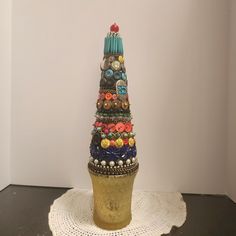 there is a small tower made out of beads and other things on top of a doily