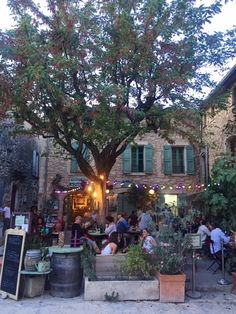 people sitting at tables under a large tree