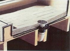 a bench made out of plywood and concrete with a drain running through the middle