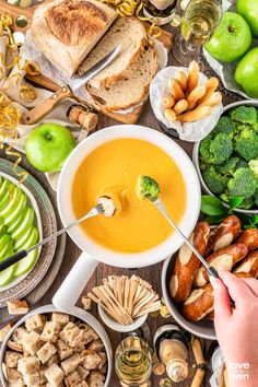 a table topped with bowls filled with soup next to sliced apples and other food items