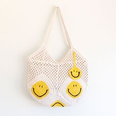 a white bag with yellow smiley faces on it hanging from a hook against a wall