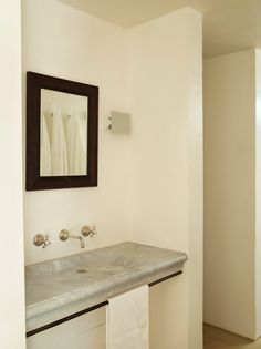 a bathroom sink sitting under a mirror next to a wall mounted faucet and towel dispenser