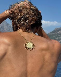 the back of a man wearing a gold sun necklace