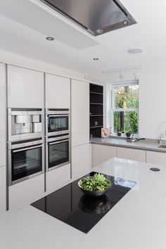 a modern kitchen with stainless steel appliances and black counter tops, along with white cabinets