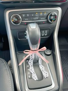 the interior of a car with a pink ribbon tied to it's center console