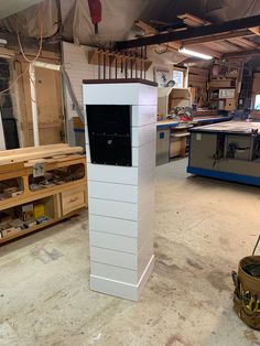 a tall white tower sitting inside of a shop next to shelves filled with woodworking tools