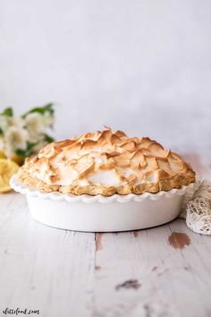 a pie sitting on top of a white table next to some yellow and white flowers