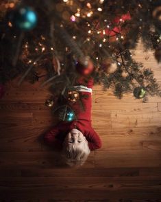 a woman laying on the floor in front of a christmas tree