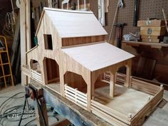 a wooden doll house sitting on top of a workbench in a shop filled with tools