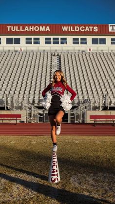 a girl in a cheerleader outfit standing on top of a pole at a stadium