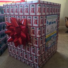 two wrapped presents sitting on the floor in front of a christmas present box with a red bow