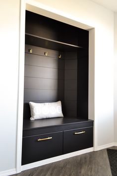 a black and white room with a bench in the corner, pillows on top of it