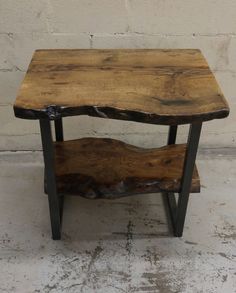 a wooden table with metal legs and a shelf on one side, against a white brick wall