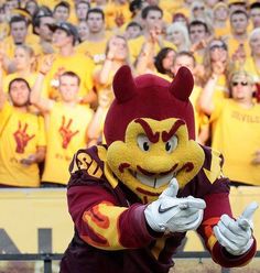 a man in a mascot costume standing next to a group of people wearing yellow and red shirts