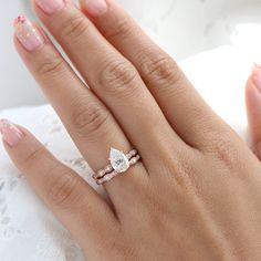 a woman's hand with two wedding rings on her left and the other hand holding an engagement ring