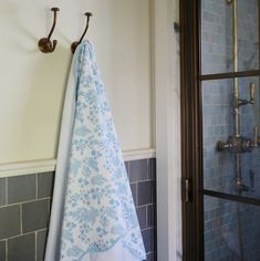 a blue and white towel hanging from a hook on a wall next to a shower