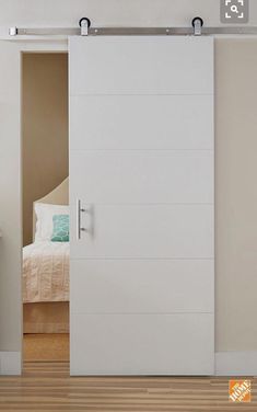 an open sliding door in a bedroom with hardwood floors and white walls, along with a bed