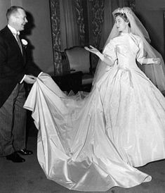 an old black and white photo of a woman in a wedding dress standing next to a man