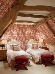 two beds in a room with red and white wallpaper