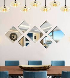 a dining room table with blue chairs and four mirrors on the wall above it,