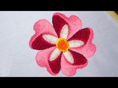 a pink and white flower with yellow center sitting on top of a piece of fabric